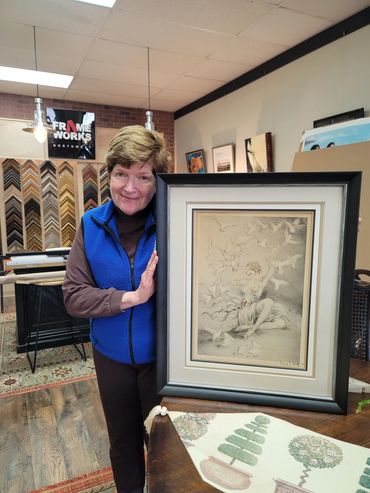 client holding custom framed artwork in frame shop