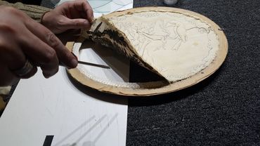 Careful hand repair of a damaged picture frame using conservation framing techniques.