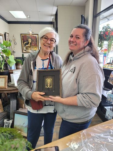 Client holding finished custom framed textile artwork at Frameworks Northwest.