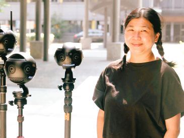 Woman standing next to virtual reality cameras.