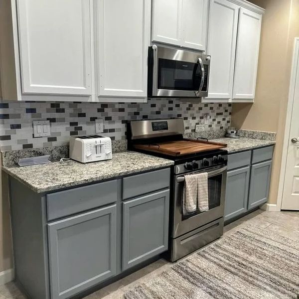 Modern kitchen with two-tone cabinets and stainless steel appliances.
