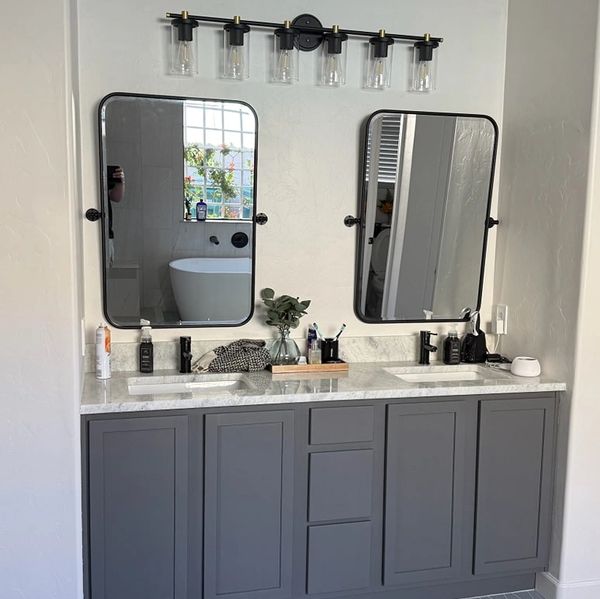 Modern bathroom vanity with two mirrors and gray cabinets.