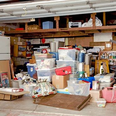 A cluttered garage filled with boxes, containers, and household items.
