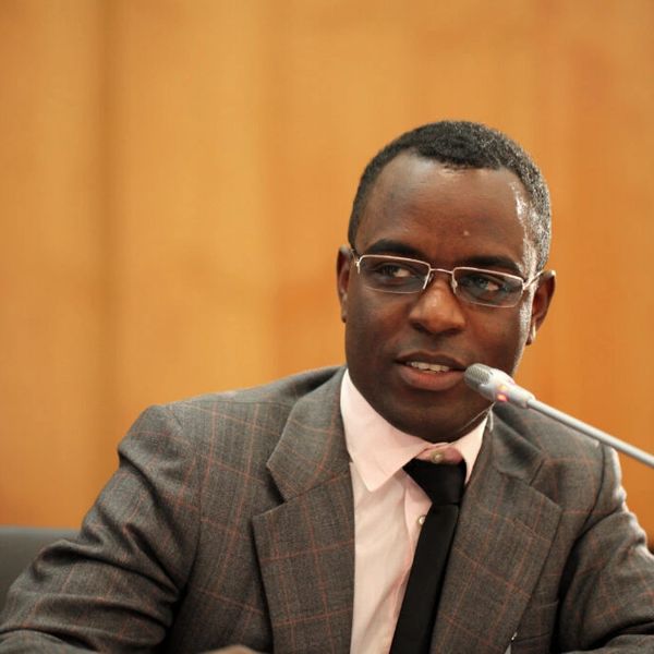 Man in suit speaking at microphone.