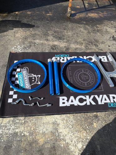 Blue bicycle rims and parts laid out on a Backyard Design mat outdoors.