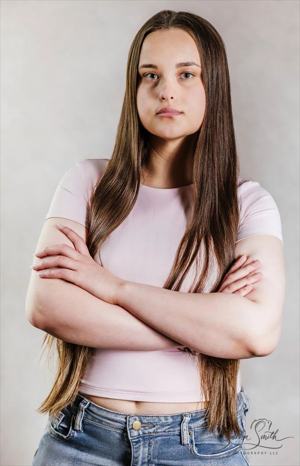 Young woman with long hair and crossed arms posing confidently.