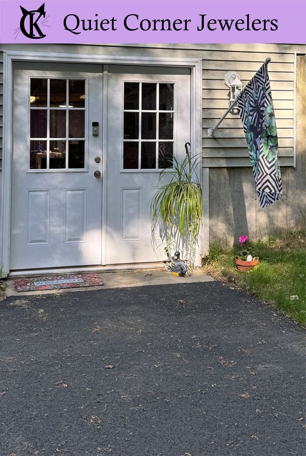 Entrance to Quiet Corner Jewelers with white double doors and decorative plants.