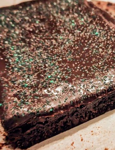 Close-up of a chocolate brownie with green sugar sprinkles.