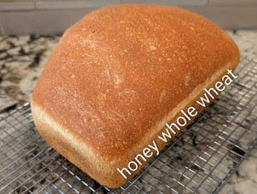 Freshly baked honey whole wheat bread cooling on a rack.