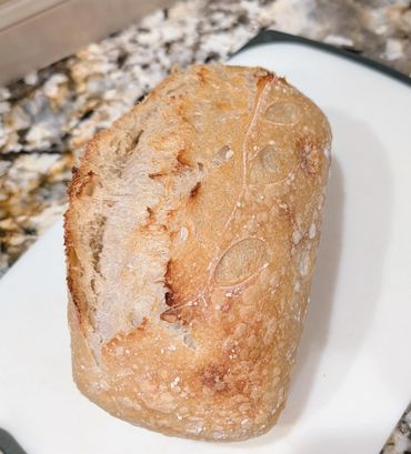 A crusty loaf of artisan bread on a white plate.