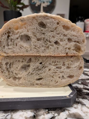 Close-up of a sliced loaf of airy artisan bread on a cutting board.