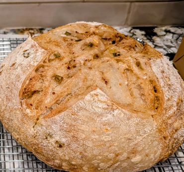 Round loaf of crusty artisan bread with a cross pattern on top.