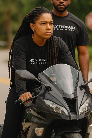 Two people in black shirts on a motorcycle, focused and serious.