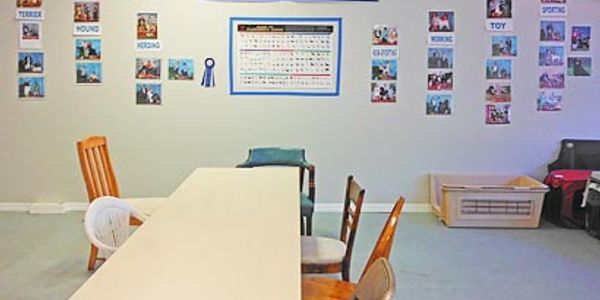 Classroom with a long table and various chairs, decorated with photos and educational posters.