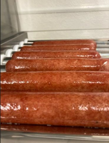 Hot dogs cooking on a roller grill.