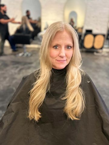 Mujer con cabello rubio y largo en salón de belleza.