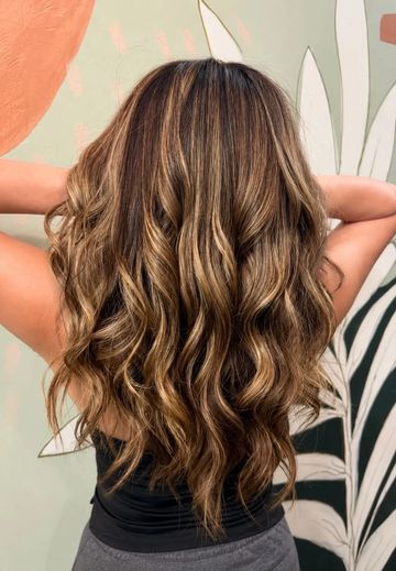 Cabello largo y rizado con reflejos dorados.