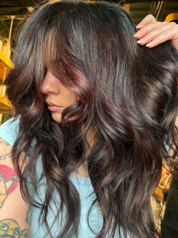 Mujer con cabello largo y ondulado oscuro mostrando su peinado.