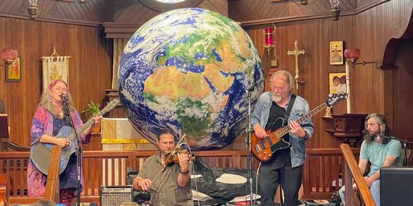 A band performing in a church with a large globe of Earth behind them.