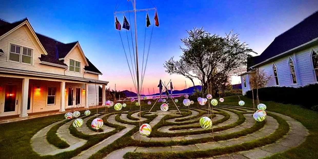 Outdoor maze with hanging lanterns and flags at dusk between two buildings.
