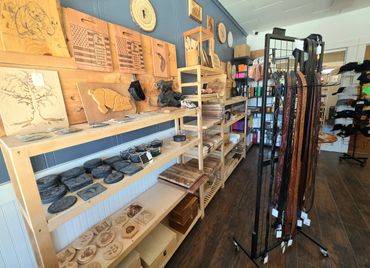 Woodcraft shop with carved wooden art, belts, and hats on display.