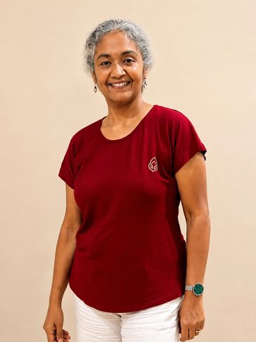 Smiling woman in a red shirt and white pants.