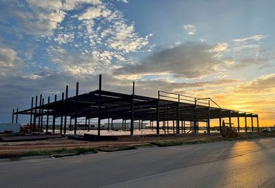 Steel framework of a building under construction at sunset.