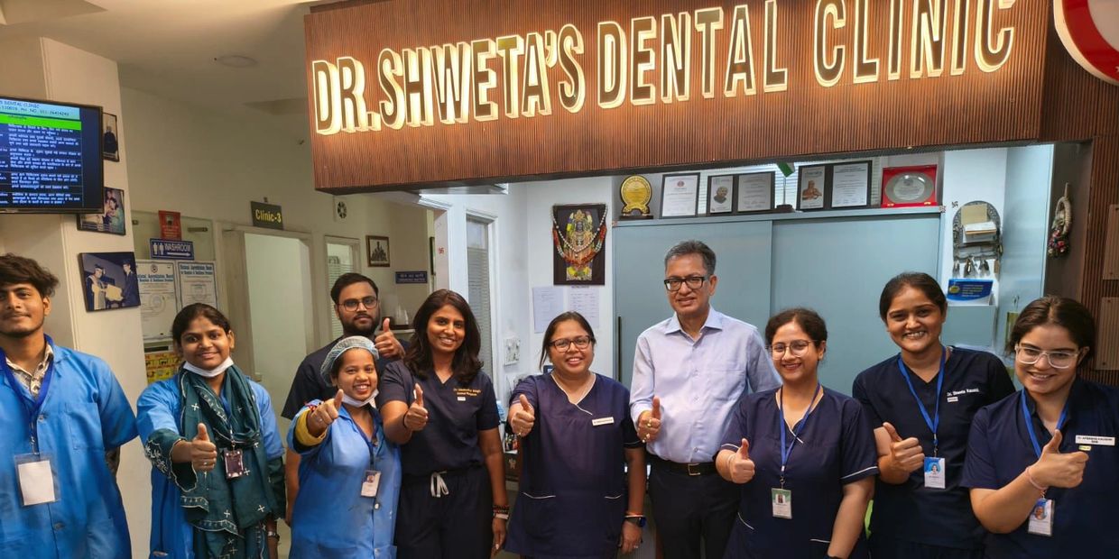 Team of dental professionals giving thumbs up at Dr. Shweta's Dental Clinic.