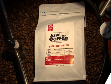 A coffee bag placed on roasted coffee beans inside a roaster.