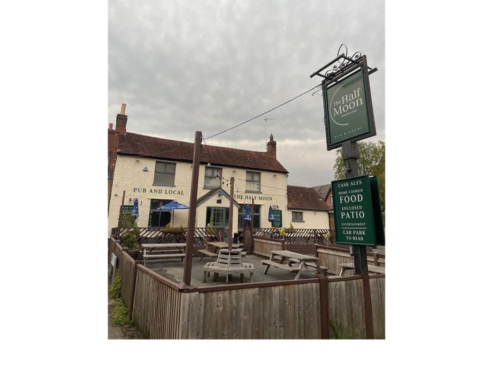 The Half Moon pub with outdoor seating and a cloudy sky.