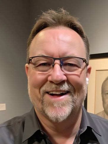 Smiling middle-aged man with glasses and earbuds indoors.