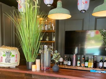 Bar counter with plants, candles, and various bottles of alcohol.