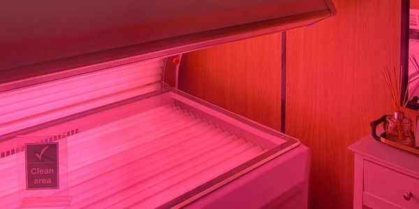 An open tanning bed emitting pink light.