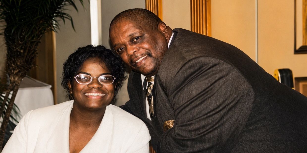 Two people smiling warmly, dressed in formal attire.