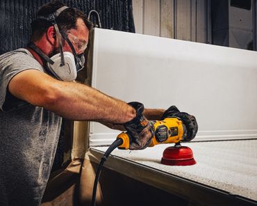Man wearing respirator mask while sanding down truck bed in preparation for spray-on bedliner.