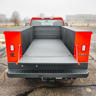Open truck bed with textured black liner and red truck exterior.
