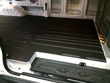 Interior of a van with a protective black floor liner installed.