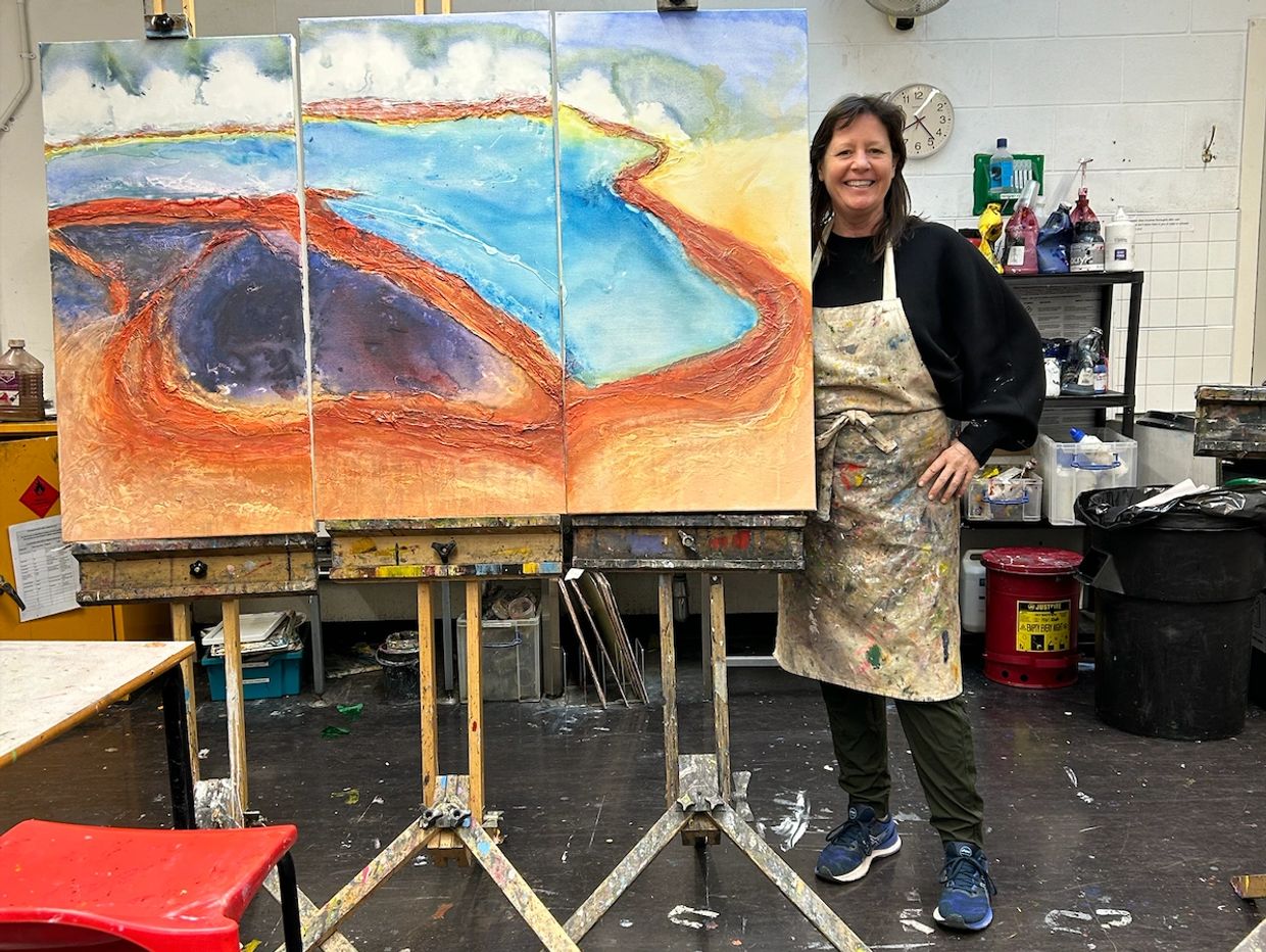 Woman standing next to abstract triptych painting in art studio.