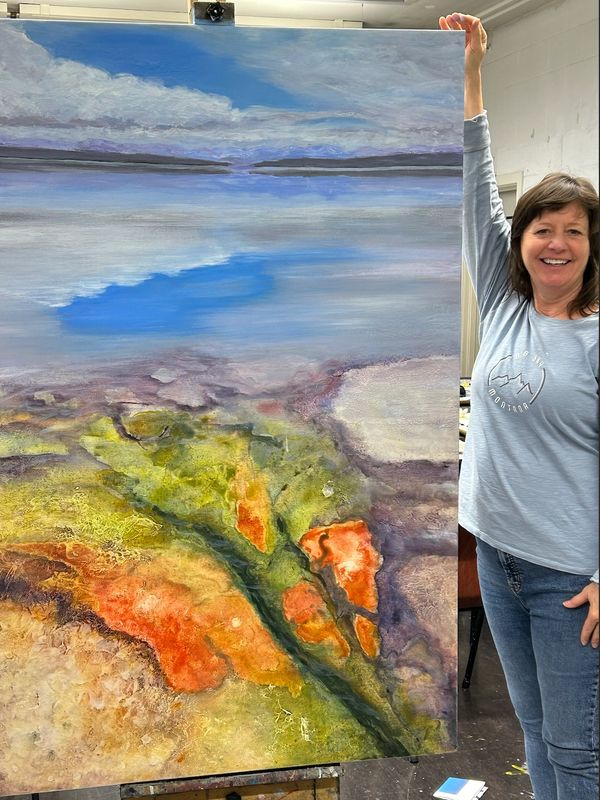Woman holding a large colorful landscape painting.