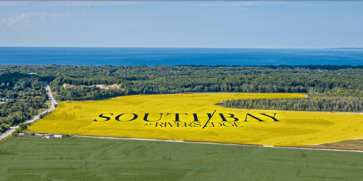 Aerial view of a large plot marked SouthBay at Rivers Edge near a forest and water body.