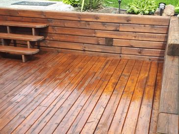 Shiny wooden deck with steps and bench.
