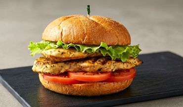 Grilled chicken sandwich with lettuce and tomato on a bun.