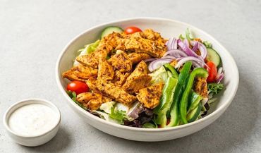 Grilled chicken salad with fresh vegetables and dressing.
