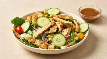 Grilled chicken salad with cucumbers and dressing.