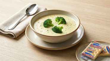 Creamy broccoli soup with crackers and spoon.