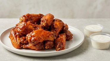 Plate of saucy buffalo chicken wings with ranch dip.