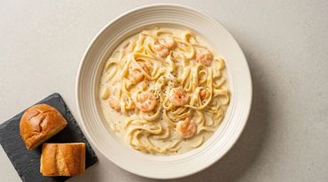 Shrimp Alfredo pasta with bread on the side.