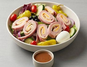 Fresh chef salad with ham rolls and dressing.