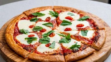 Margherita pizza with mozzarella and basil on wooden board.