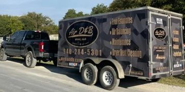 A pickup truck towing a service trailer for air duct cleaning.